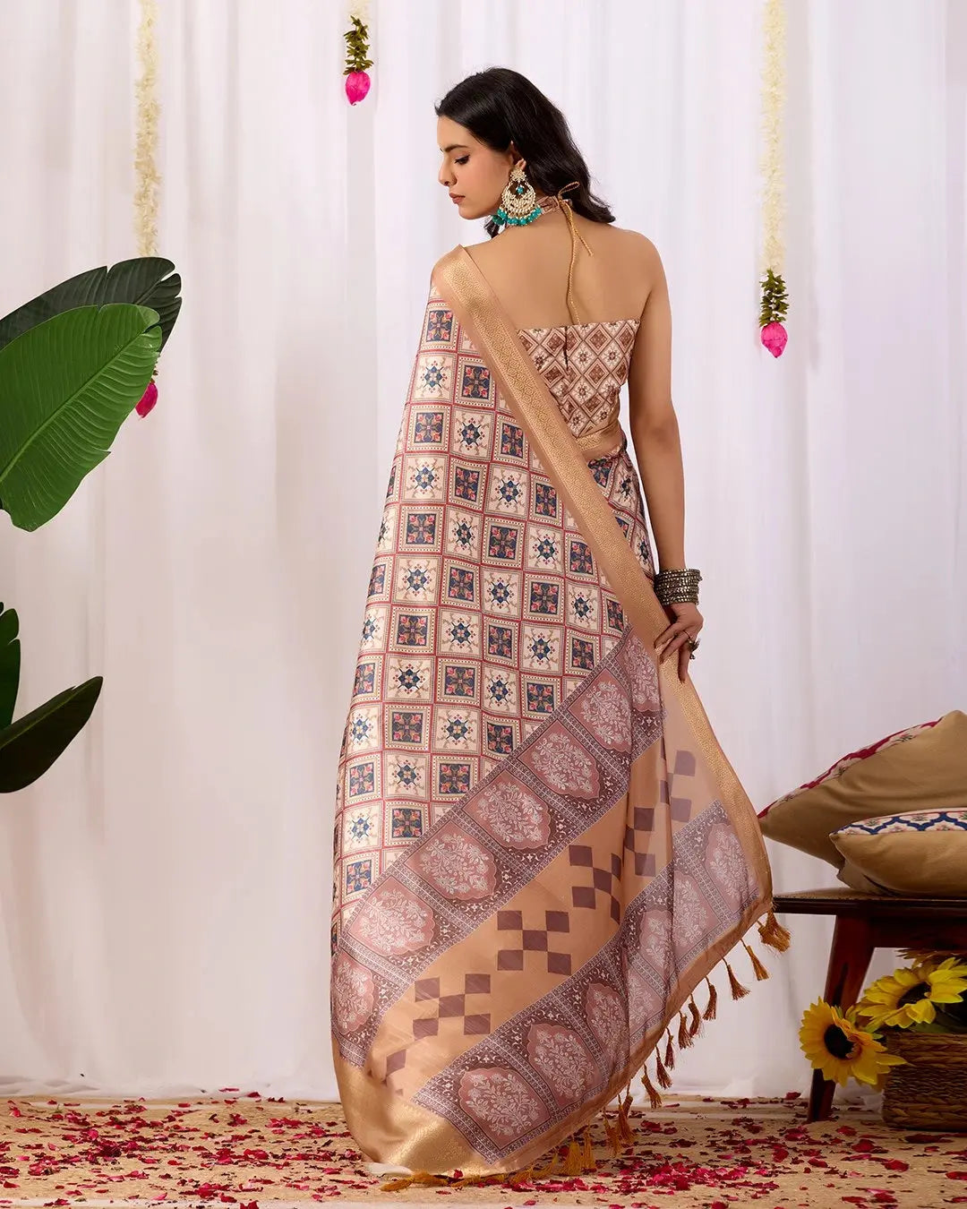 Woman wearing a patterned saree with a white curtain background